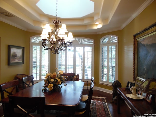 dining space with an inviting chandelier, a raised ceiling, ornamental molding, and dark hardwood / wood-style floors