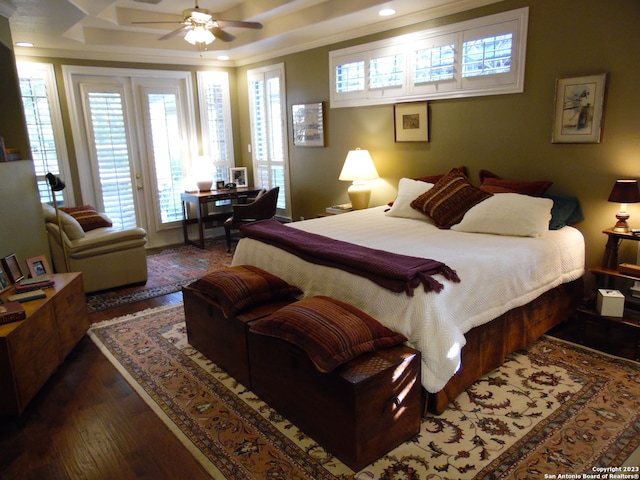 bedroom featuring dark wood-type flooring, ceiling fan, access to exterior, ornamental molding, and a tray ceiling