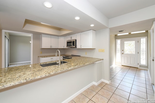 kitchen with appliances with stainless steel finishes, sink, light tile floors, white cabinets, and light stone counters