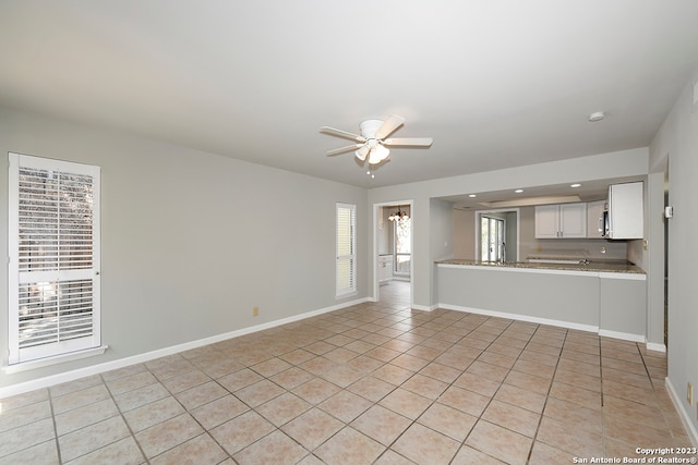 unfurnished living room featuring ceiling fan and light tile floors