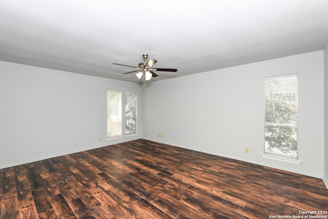 empty room with plenty of natural light, ceiling fan, and dark hardwood / wood-style flooring