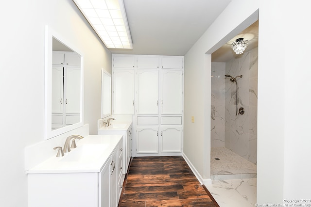 bathroom featuring double sink vanity, a tile shower, and wood-type flooring