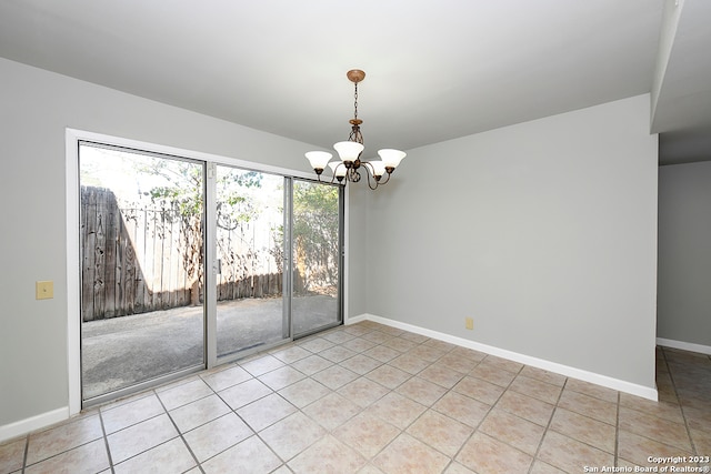 tiled spare room with an inviting chandelier