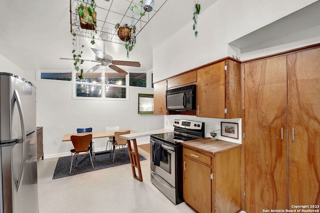 kitchen with ceiling fan, a towering ceiling, and stainless steel appliances