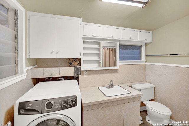 interior space featuring toilet, tile flooring, sink, and washer / dryer