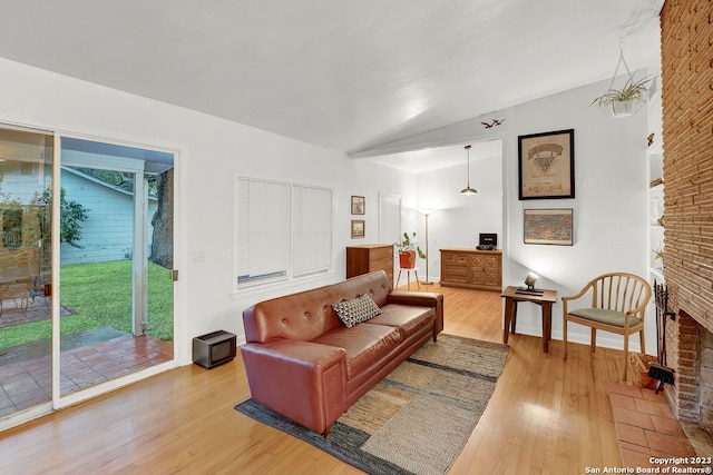 living room with lofted ceiling, light wood-type flooring, and a fireplace