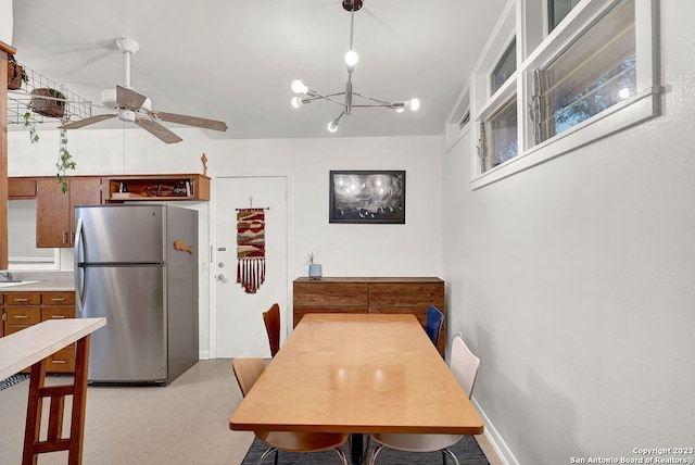 dining room with ceiling fan with notable chandelier, sink, and light colored carpet