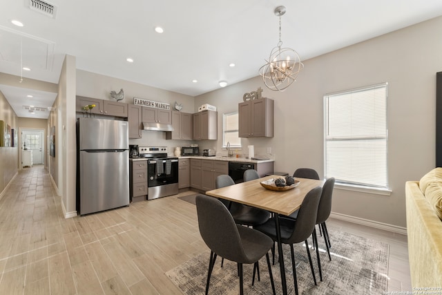 dining area featuring light hardwood / wood-style floors, sink, and an inviting chandelier