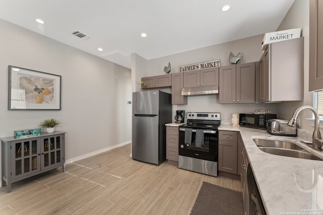 kitchen with light hardwood / wood-style flooring, appliances with stainless steel finishes, sink, gray cabinetry, and light stone counters