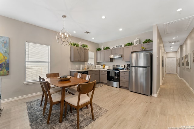 dining room featuring a notable chandelier, sink, and light hardwood / wood-style flooring