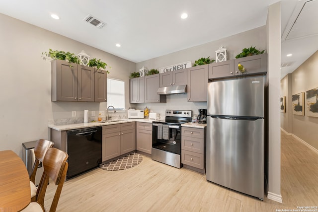 kitchen featuring stainless steel appliances, light hardwood / wood-style flooring, sink, gray cabinetry, and light stone counters