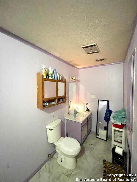 bathroom with a textured ceiling, tile floors, toilet, and vanity with extensive cabinet space