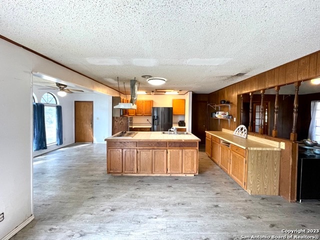 kitchen with ceiling fan, black appliances, light hardwood / wood-style flooring, a center island, and a textured ceiling