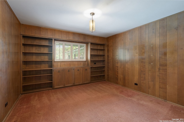 carpeted empty room with wood walls