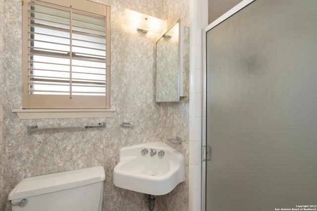 bathroom featuring a shower with shower door and toilet