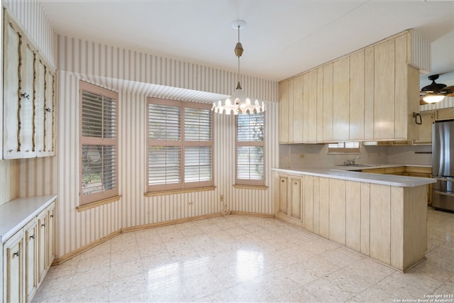 kitchen with light tile flooring, pendant lighting, stainless steel refrigerator, ceiling fan with notable chandelier, and kitchen peninsula