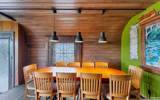 dining space featuring wood walls and vaulted ceiling