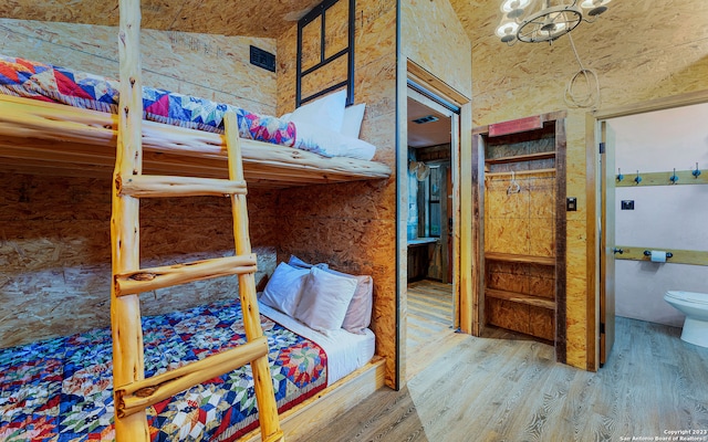 bedroom with a notable chandelier, light hardwood / wood-style flooring, and ensuite bath