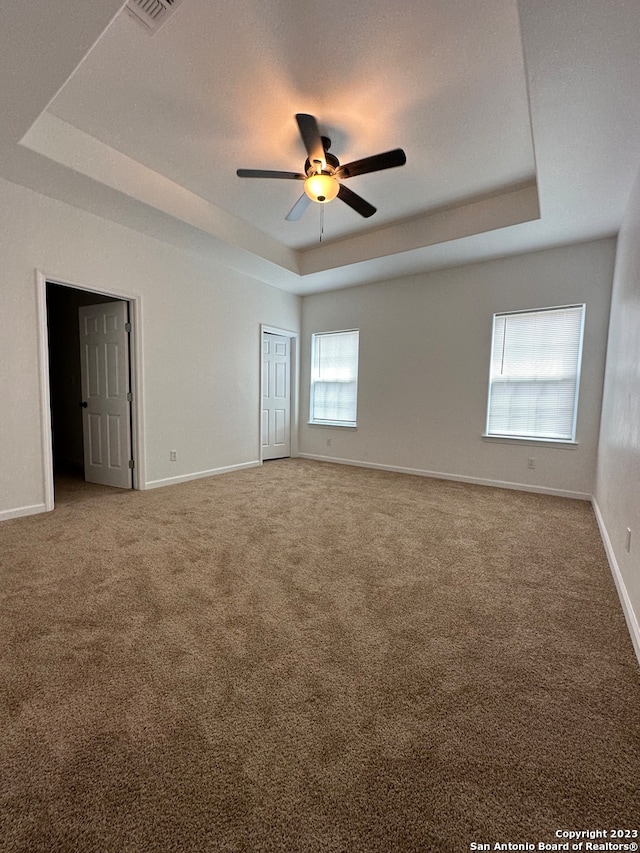 carpeted spare room featuring ceiling fan and a tray ceiling