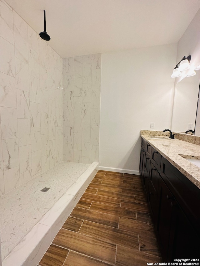 bathroom featuring dual vanity and a tile shower