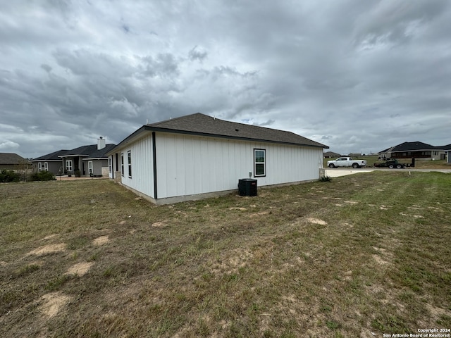 rear view of house featuring central AC and a lawn