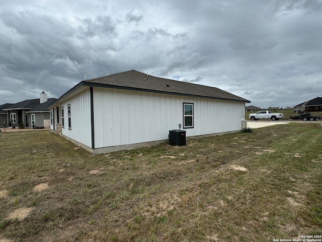 back of property featuring central AC unit and a lawn