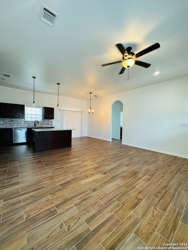 unfurnished living room featuring sink and ceiling fan with notable chandelier