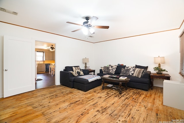 living room with ornamental molding, ceiling fan, and light hardwood / wood-style flooring