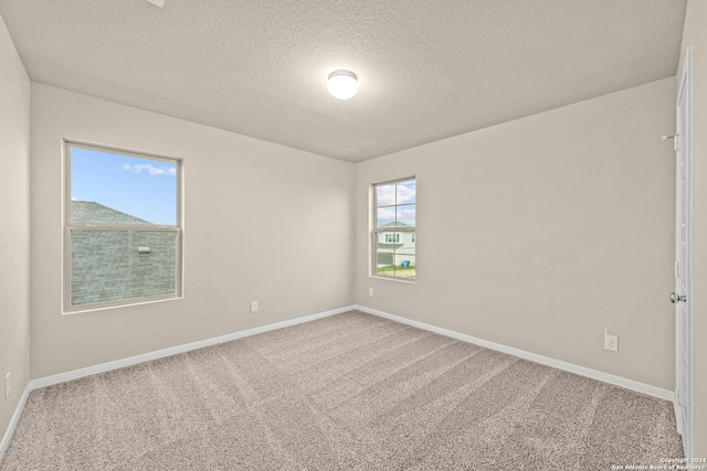 unfurnished room with carpet flooring, baseboards, and a textured ceiling