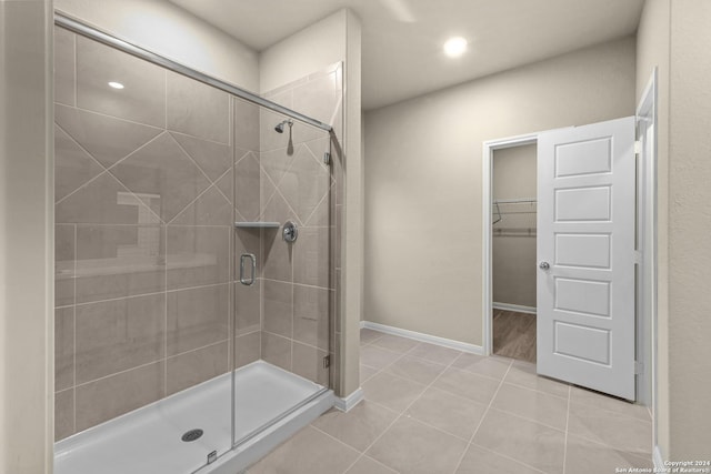 bathroom featuring a spacious closet, a shower stall, baseboards, recessed lighting, and tile patterned floors