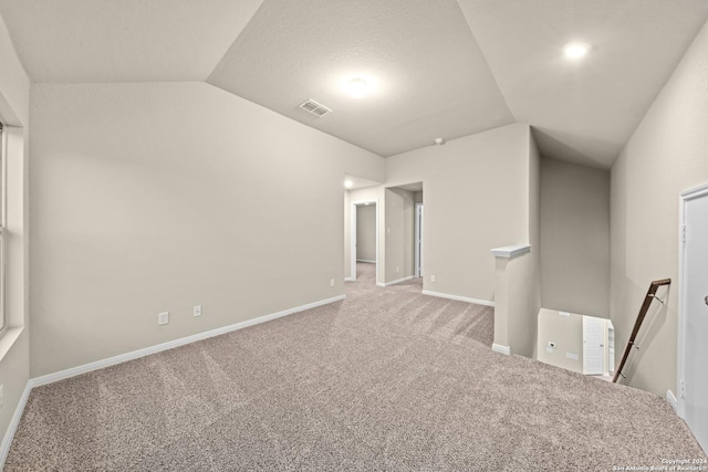 empty room featuring visible vents, carpet flooring, baseboards, and lofted ceiling