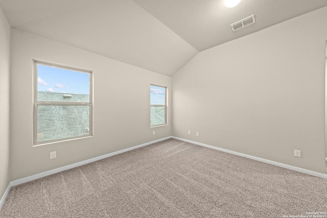 spare room with baseboards, visible vents, carpet floors, lofted ceiling, and a textured ceiling