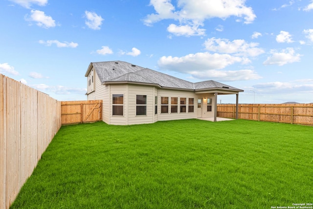 rear view of property with a patio, a lawn, a fenced backyard, and roof with shingles