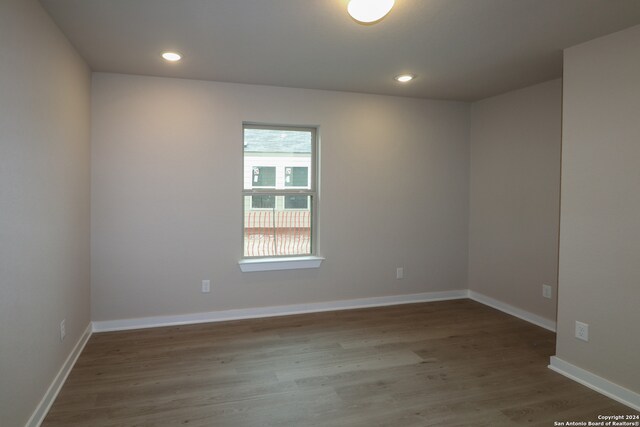 empty room with recessed lighting, wood finished floors, and baseboards