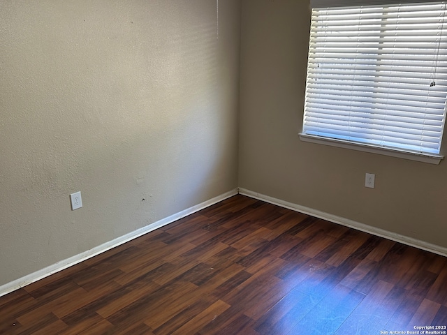 unfurnished room featuring dark wood-type flooring and a healthy amount of sunlight