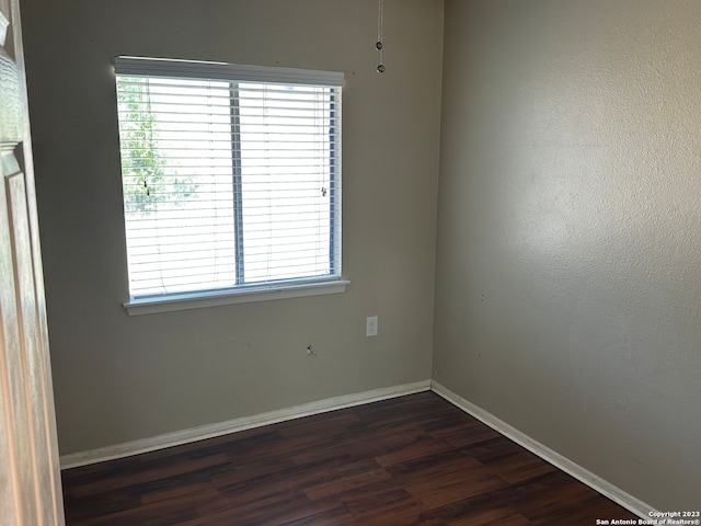 unfurnished room featuring dark hardwood / wood-style flooring and a healthy amount of sunlight