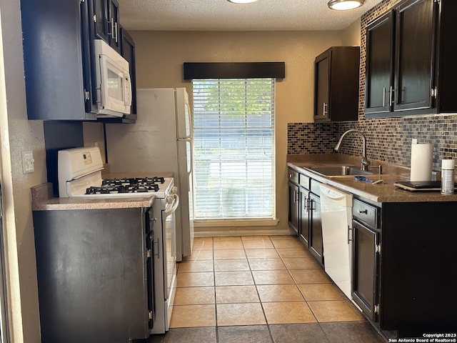 kitchen featuring light tile floors, a textured ceiling, backsplash, white appliances, and sink