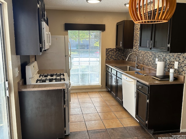 kitchen featuring tasteful backsplash, white appliances, light tile floors, a textured ceiling, and sink