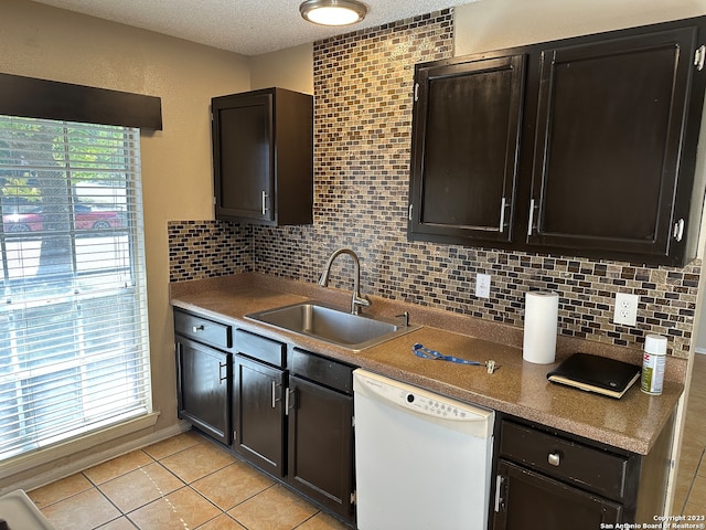 kitchen with backsplash, dishwasher, sink, and light tile flooring