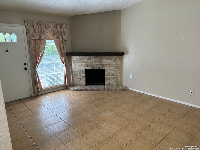 unfurnished living room with a brick fireplace, light tile floors, and a textured ceiling