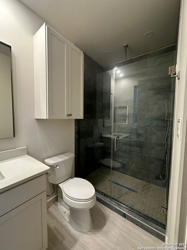 bathroom with toilet, tile patterned flooring, walk in shower, and vanity