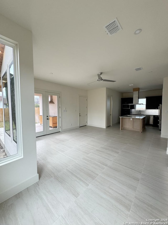 unfurnished living room featuring french doors and ceiling fan