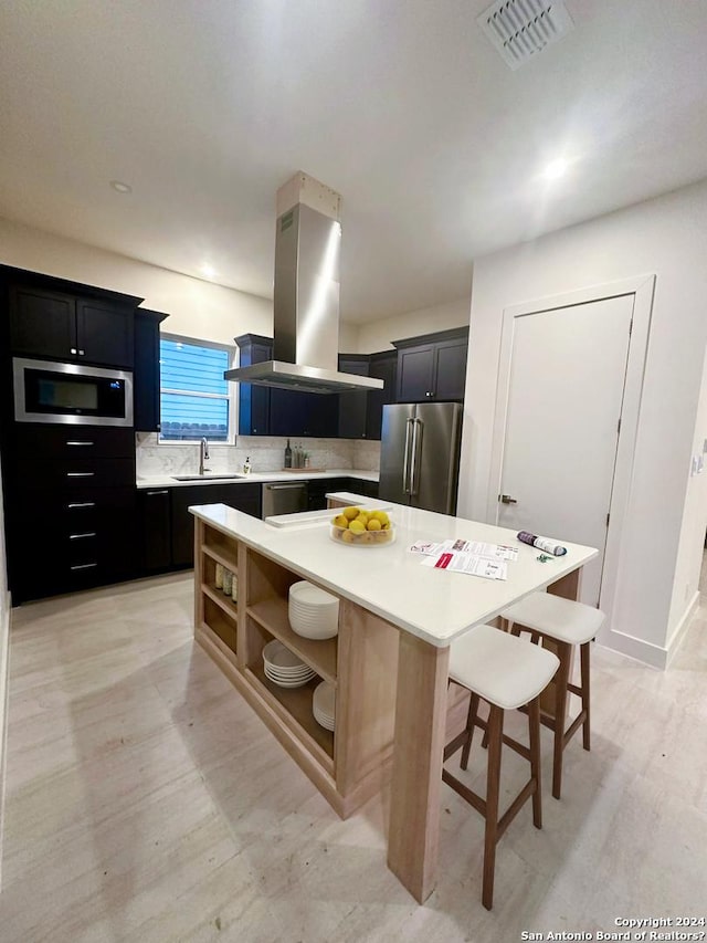 kitchen featuring stainless steel appliances, a center island, a kitchen bar, island exhaust hood, and decorative backsplash