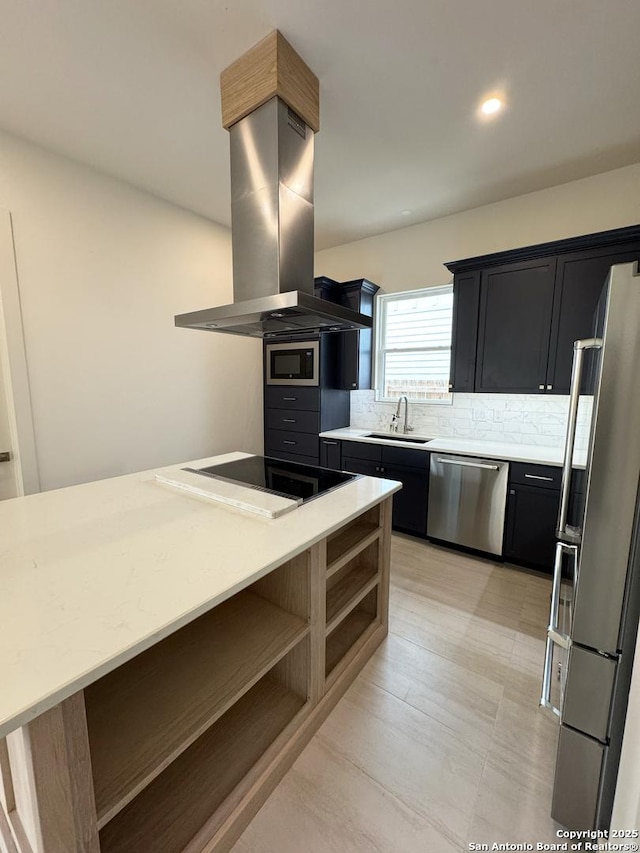 kitchen with sink, island range hood, tasteful backsplash, and appliances with stainless steel finishes