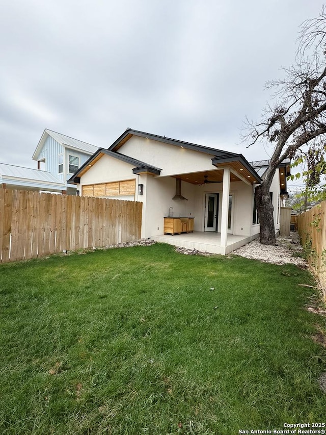 rear view of house with ceiling fan, a patio, and a lawn