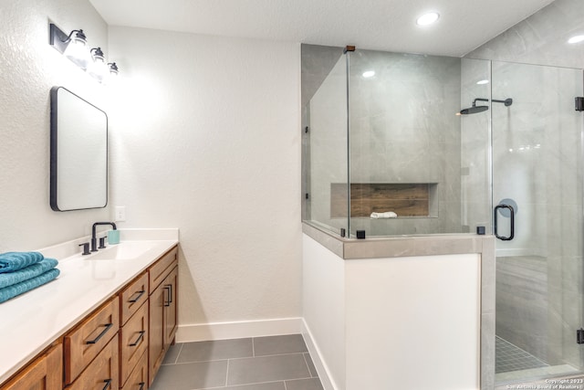 bathroom with tile patterned flooring, vanity, and walk in shower