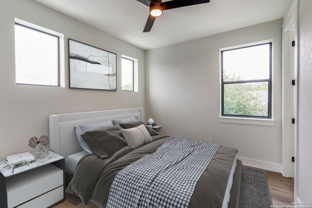 bedroom with multiple windows, light hardwood / wood-style flooring, and ceiling fan