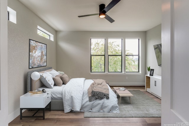 bedroom with multiple windows, hardwood / wood-style floors, and ceiling fan