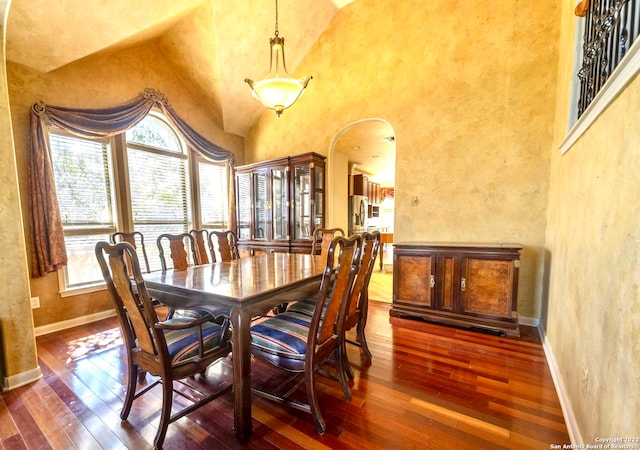 dining area featuring high vaulted ceiling and dark hardwood / wood-style flooring