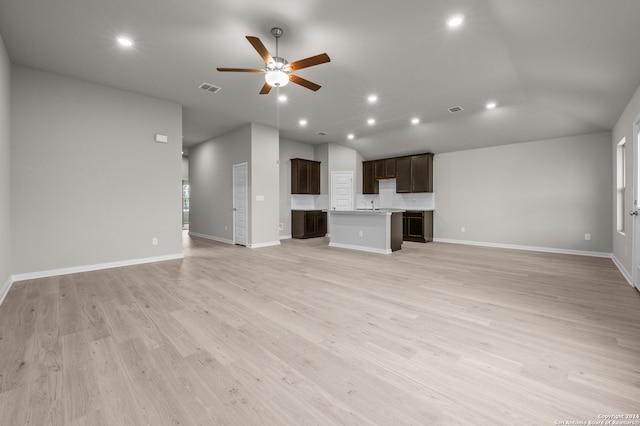 unfurnished living room with ceiling fan, sink, lofted ceiling, and light hardwood / wood-style floors